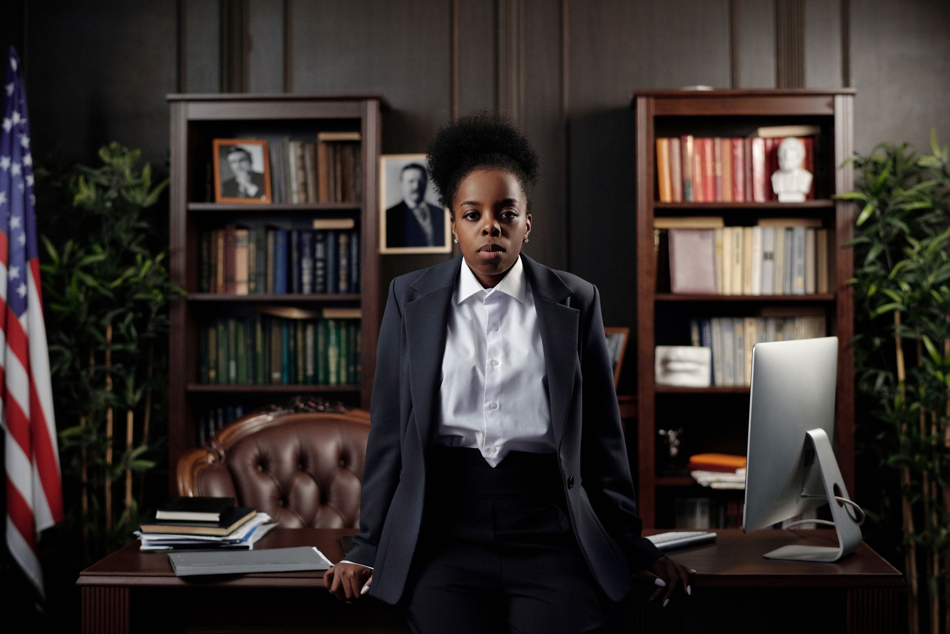 Young Black female lawyer in a suit in an office with a flag and books