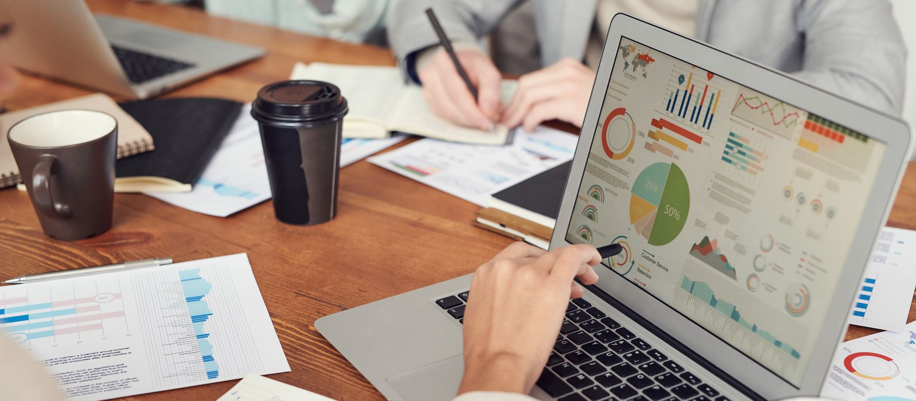 A person analyzes data visualizations on a laptop screen, showing business metrics