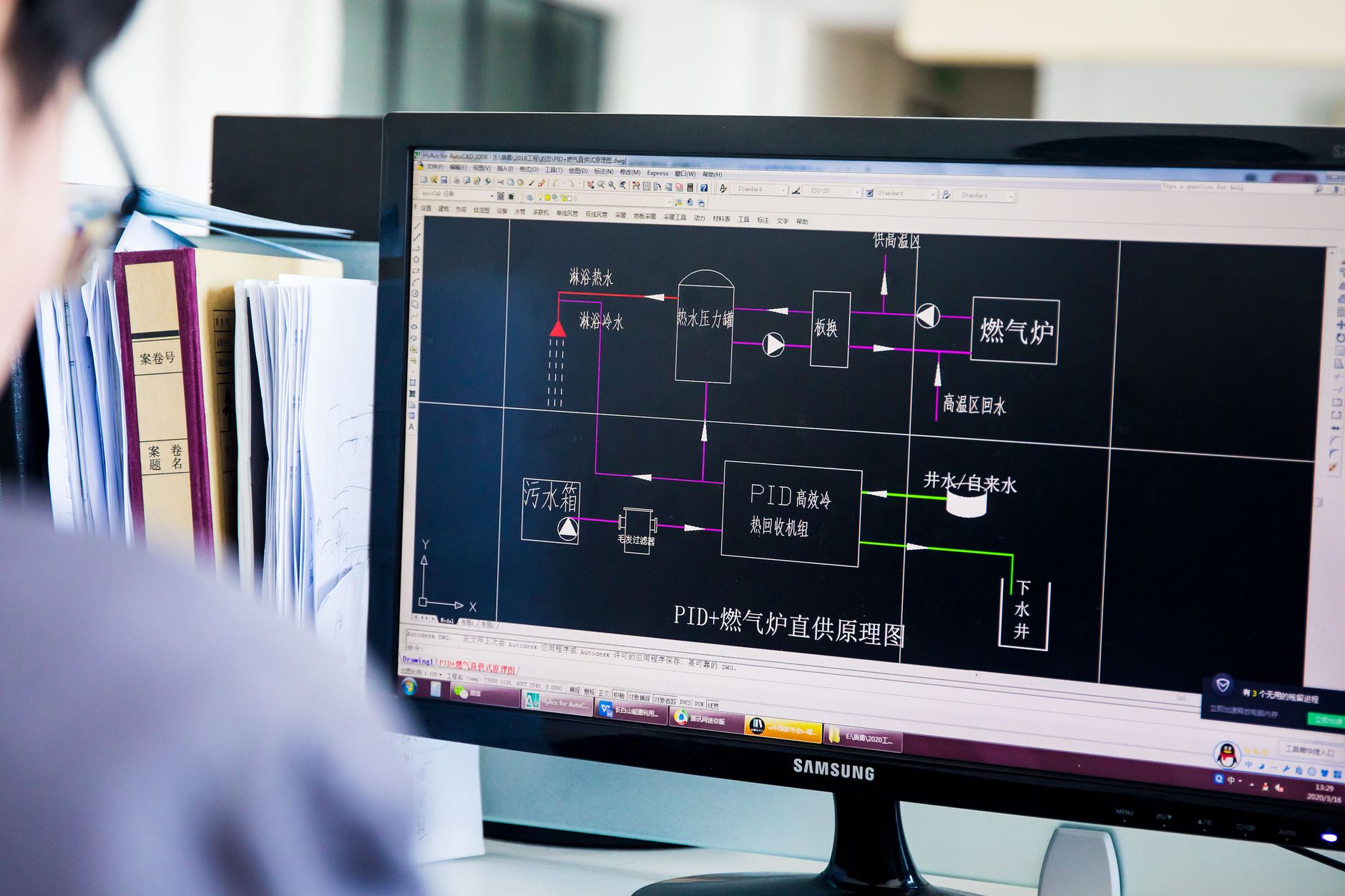 A person reviews a detailed technical diagram on a computer monitor